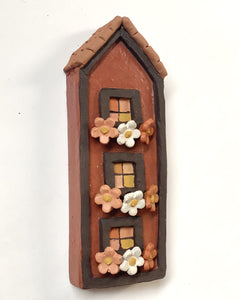 Casa marrom com flores coloridas nas jardineiras (parede)